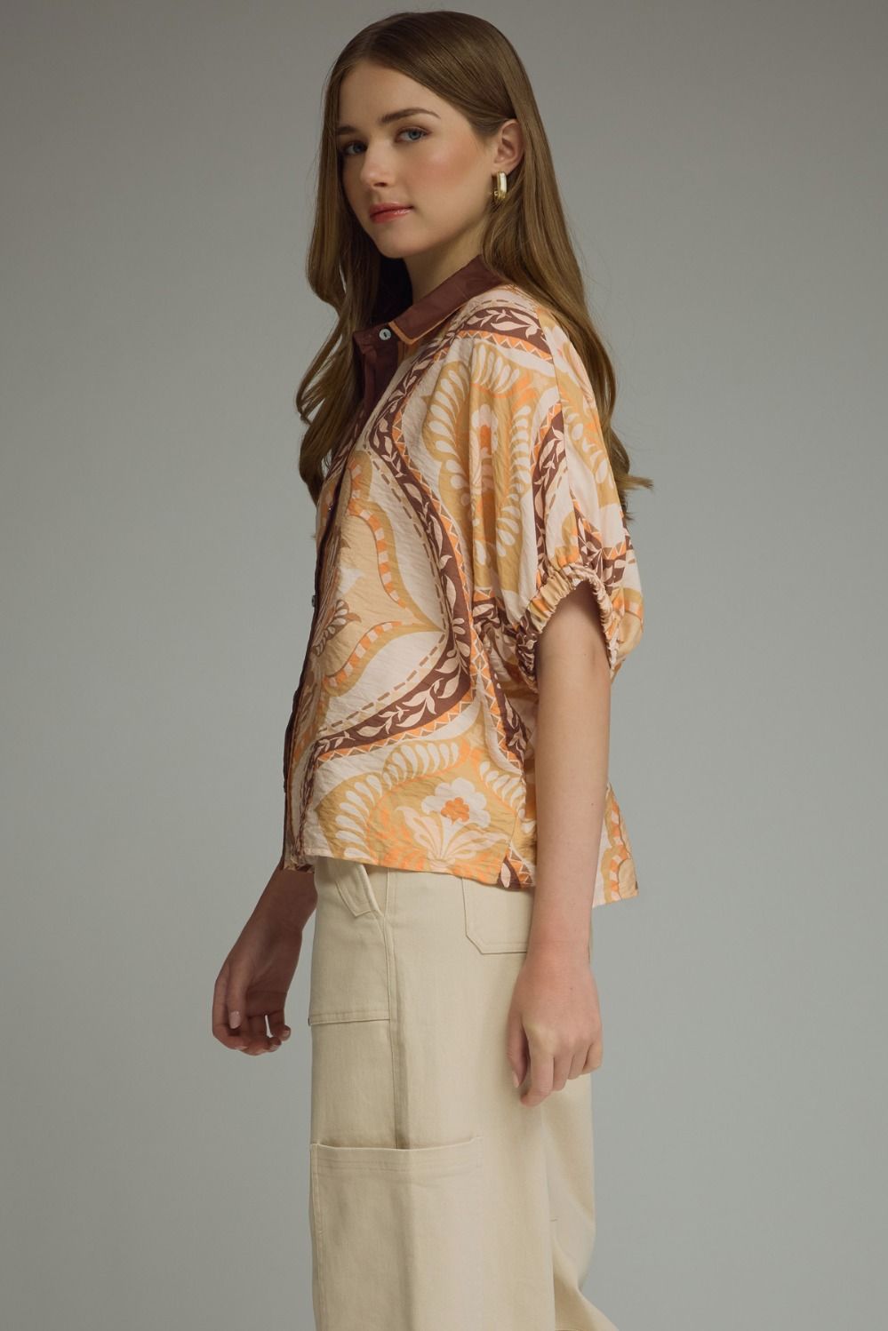 A lightweight abstract print blouse featuring relaxed dolman sleeves, contrast trim details, and an effortlessly chic silhouette.
