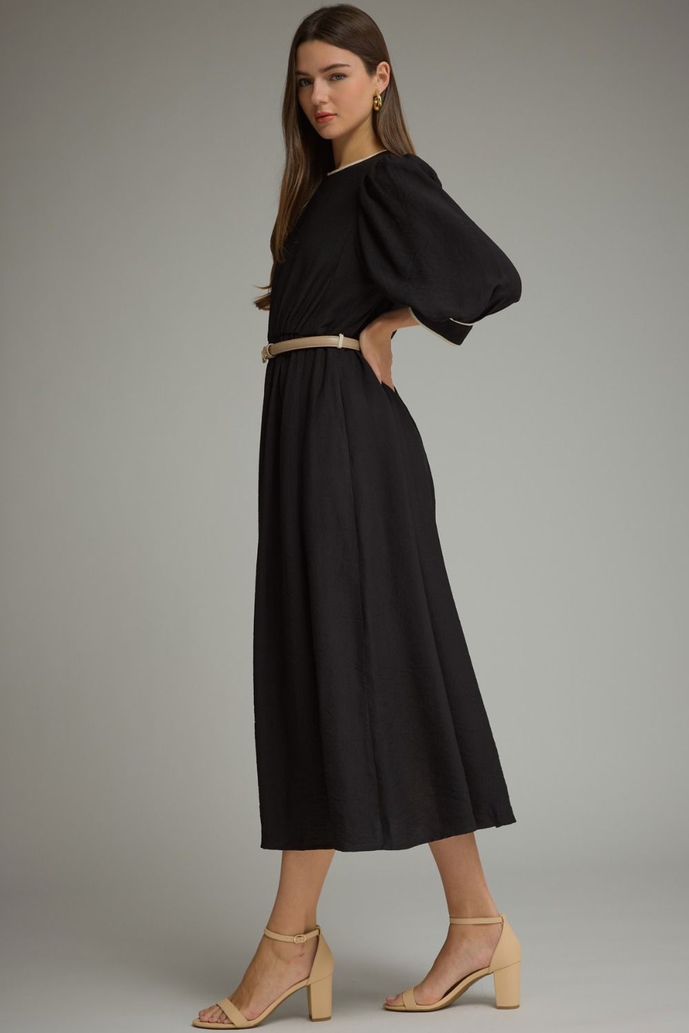 A polished ¾-sleeve midi dress featuring feminine puff sleeves, contrast piping, a defined elastic waist, and a removable buckle belt.