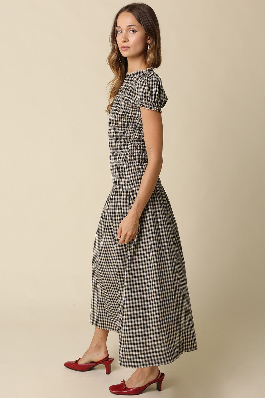 A romantic plaid maxi dress featuring soft puff sleeves, a fitted smocked bodice, and a flowing gathered skirt for an effortlessly feminine silhouette.