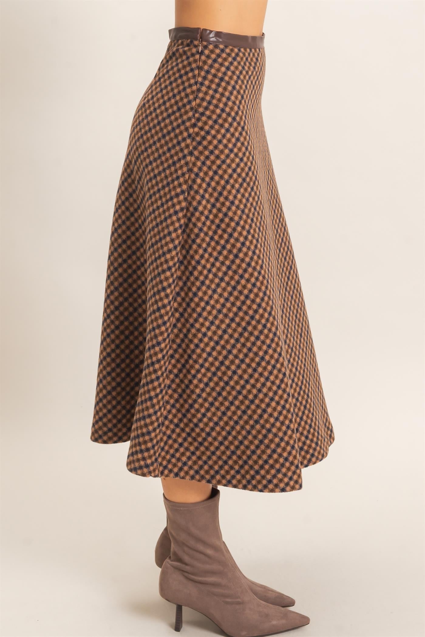 A sophisticated checkered A-line midi skirt featuring a sleek faux leather waistband and flattering flare for effortlessly polished style.

