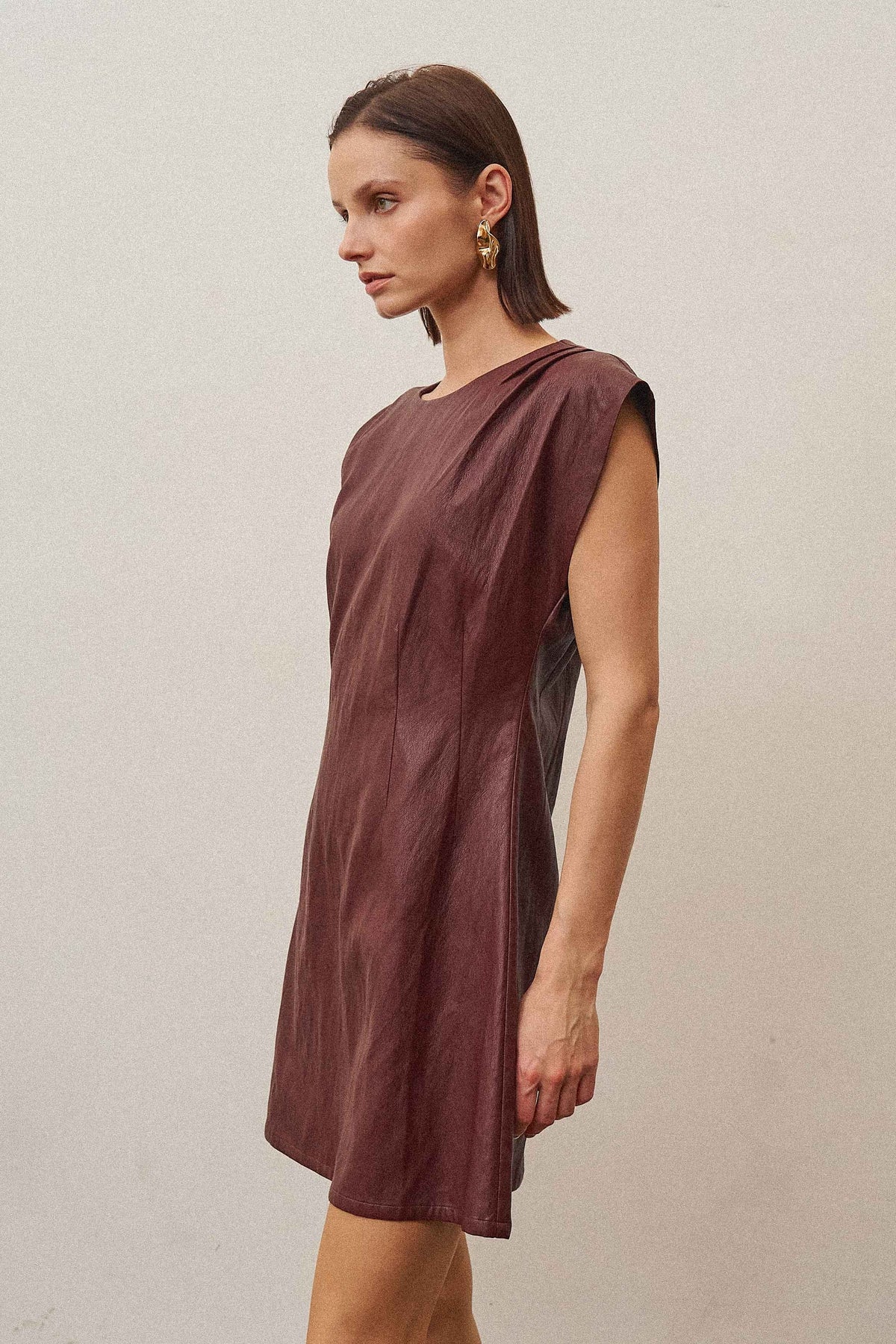 A sleek vegan leather mini dress featuring a subtle shimmering finish for a chic, statement-making look.