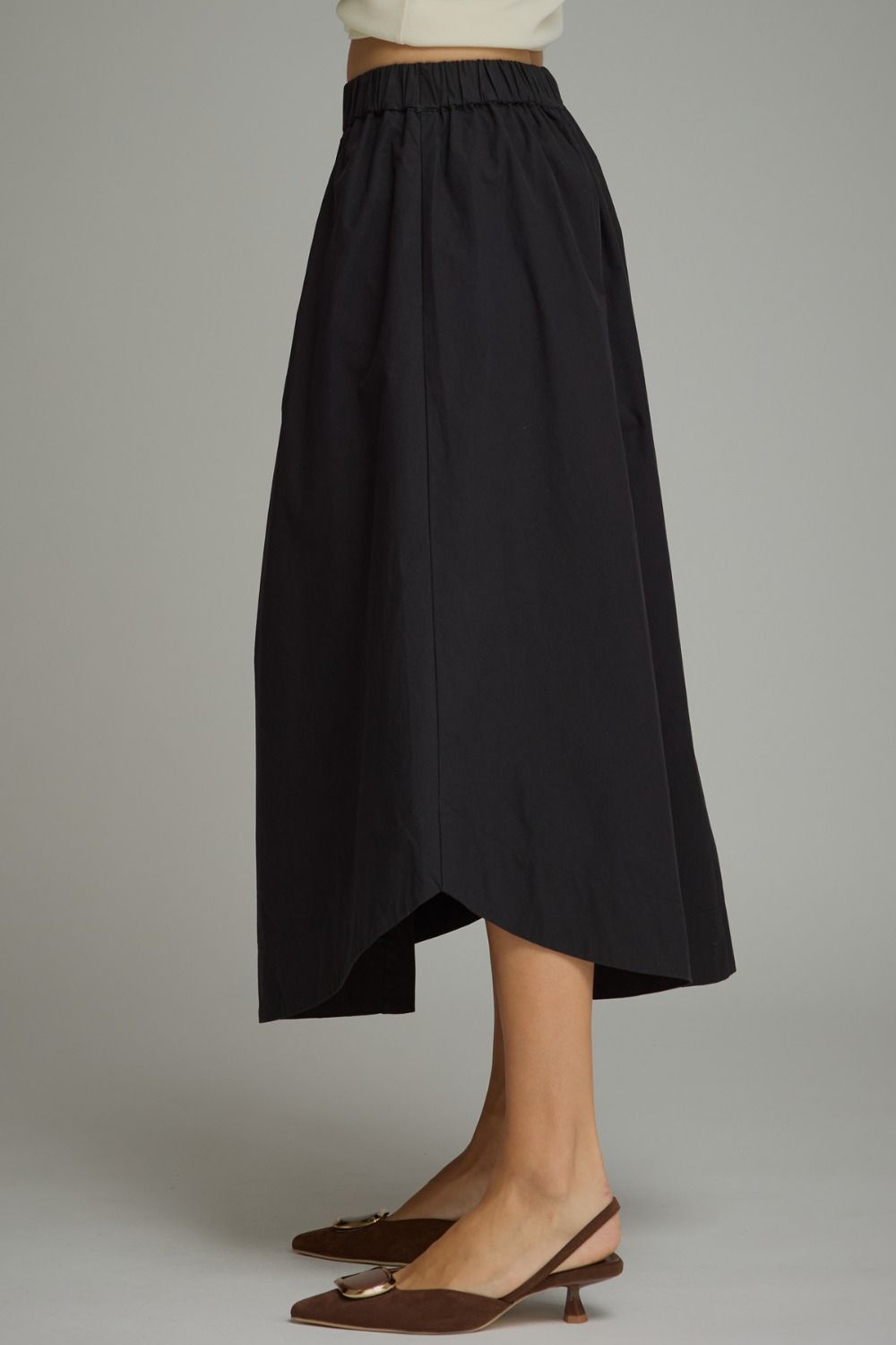 A timeless midi skirt featuring a button-front design, comfortable elastic waistband, and functional side pockets for effortless everyday elegance.

