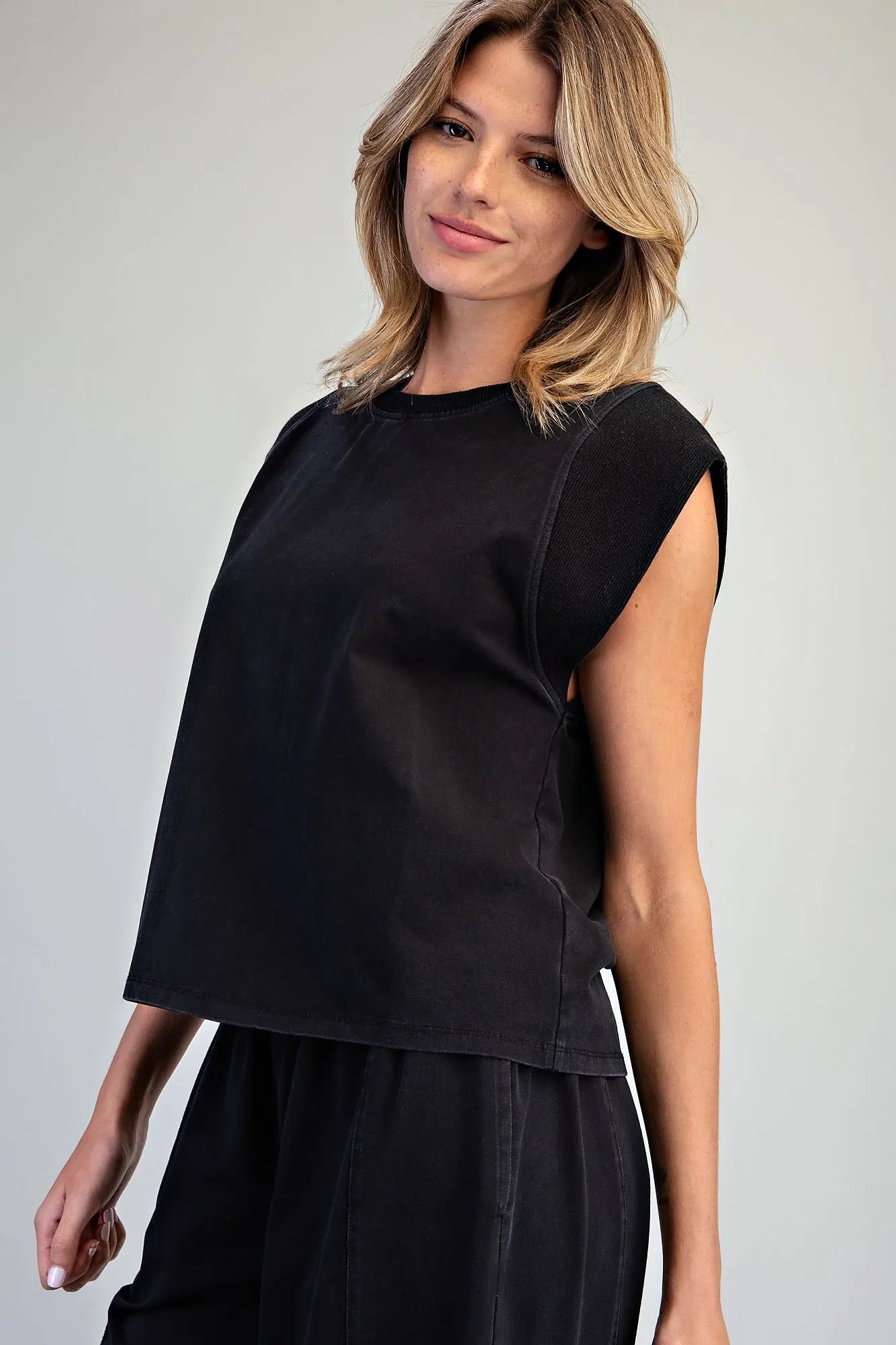 A relaxed washed top featuring structured cap shoulders, ribbed trim detailing, and a minimalist silhouette for effortless everyday style.
