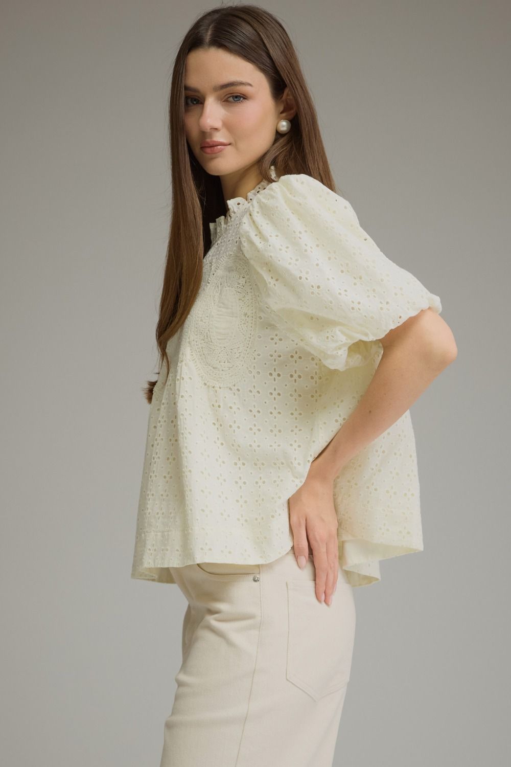 A feminine short sleeve top featuring a romantic ruffled neckline, delicate eyelet detailing, and crochet trim for a beautifully textured boutique look.