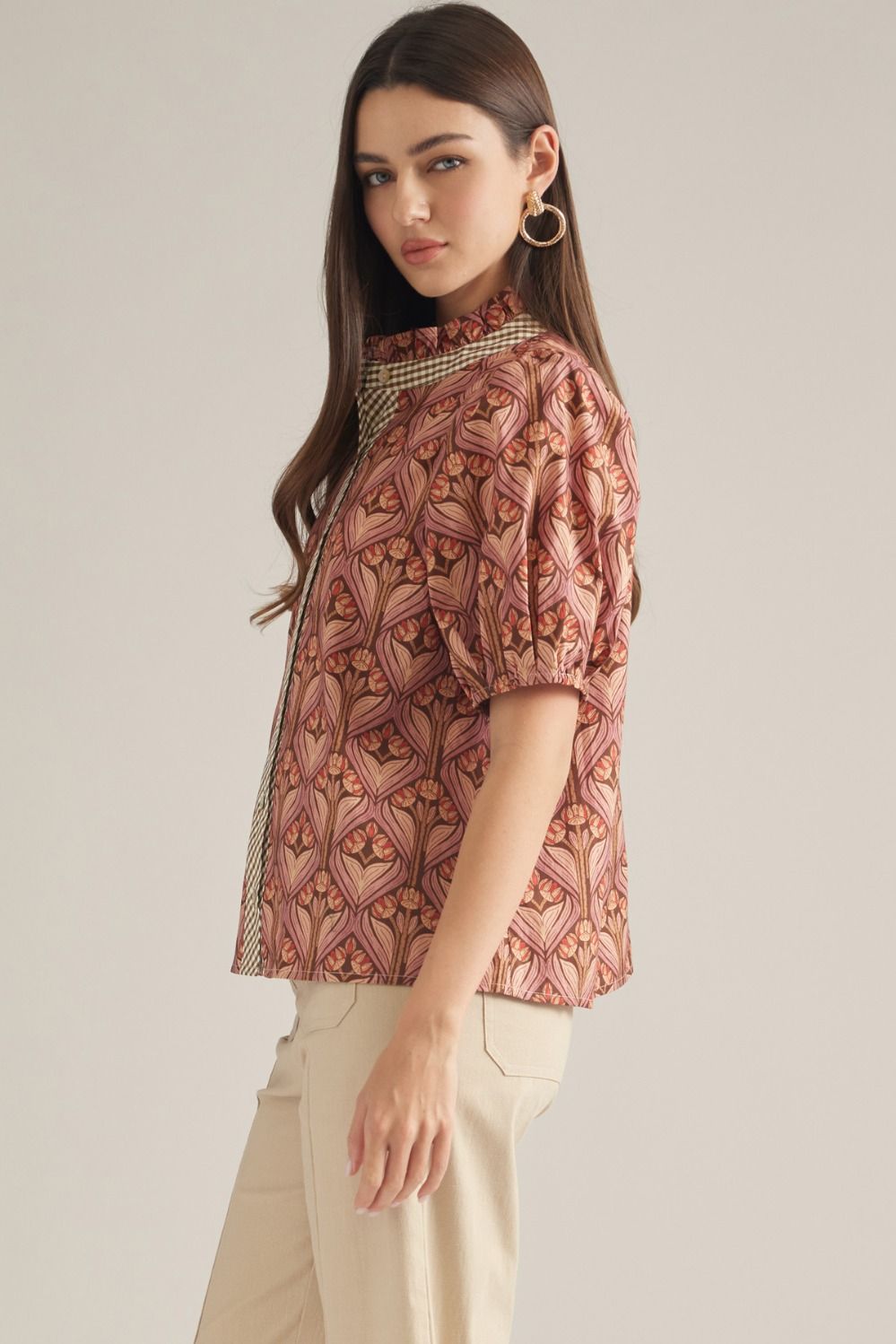 A feminine short sleeve top featuring a charming ruffled neckline, contrast trim, and button-front closure in a lightweight woven fabric.