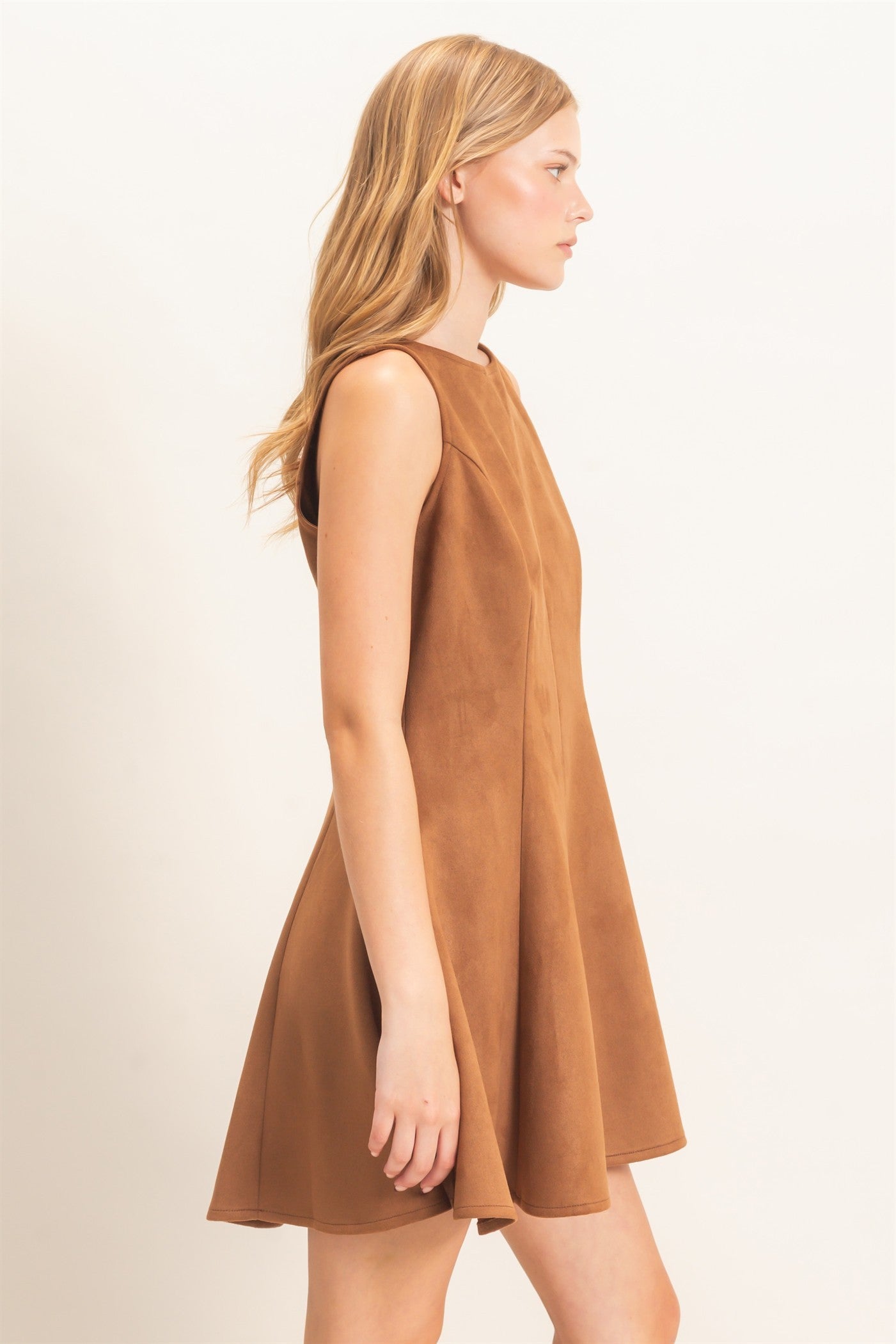 A sophisticated sleeveless suede mini dress with a classic round neckline and flattering flared silhouette that effortlessly transitions from day to night.
