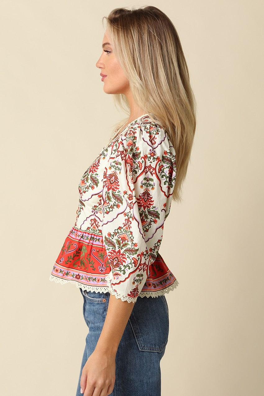 A feminine floral peplum blouse featuring voluminous puff sleeves, delicate lace trim, and a flattering split neckline for effortless boutique style.