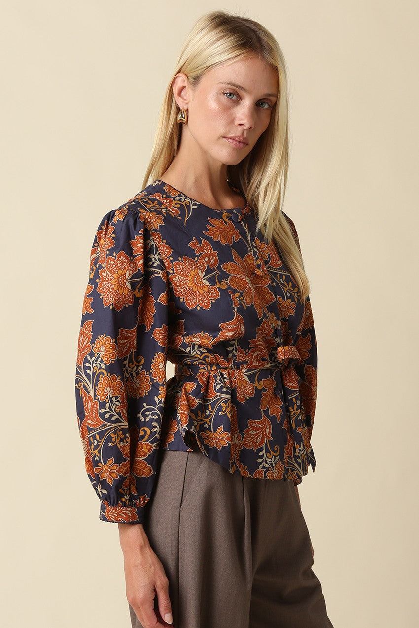 A feminine floral blouse featuring puff sleeves, a flattering peplum silhouette, and a front tie waist for an effortlessly polished look.

