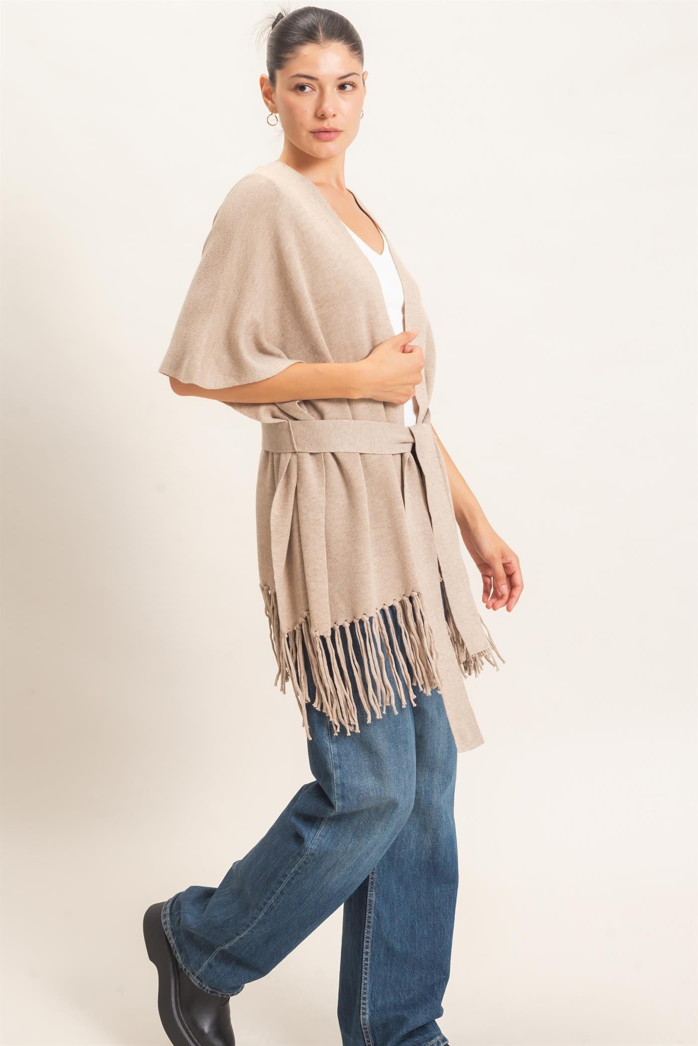 A chic open-front kimono sweater with wide sleeves, a self-tie waist, and statement fringe trim that adds effortless movement to any outfit.