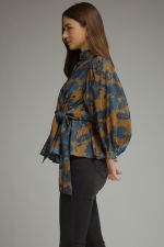 A feminine floral peplum top featuring romantic balloon sleeves, a stand collar, and a flattering tie waist for a beautifully defined silhouette.a