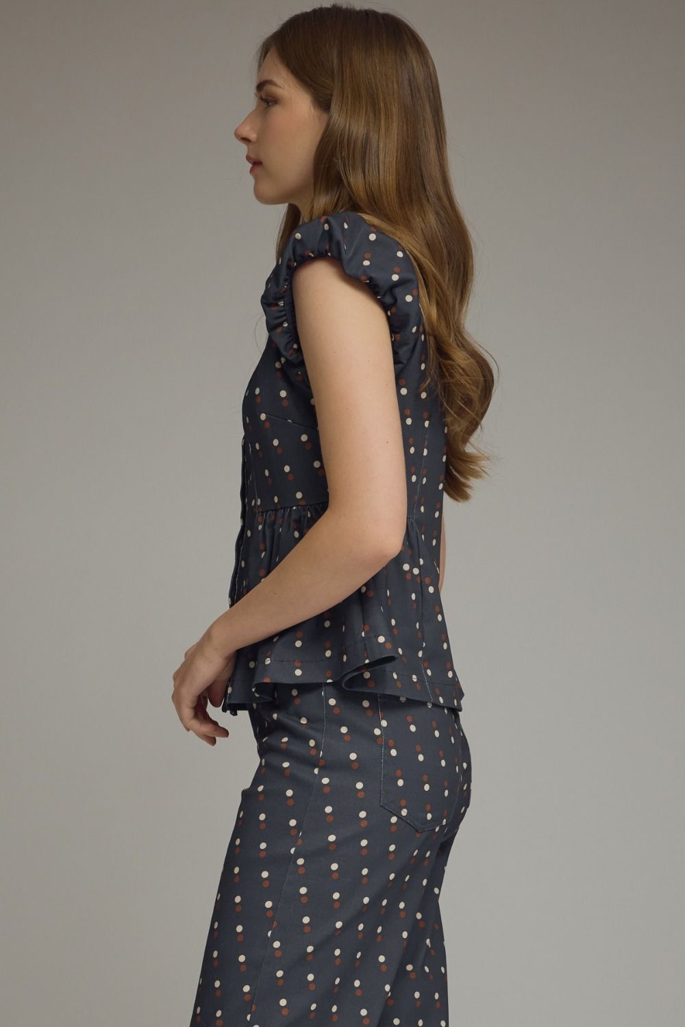 A playful polka dot denim top featuring cap sleeves, a collared neckline, and a flattering peplum hem for effortlessly feminine style.