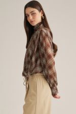 A sophisticated plaid blouse featuring a high neckline, elegant draped crossover front, self-tie back detail, and button cuffs.
