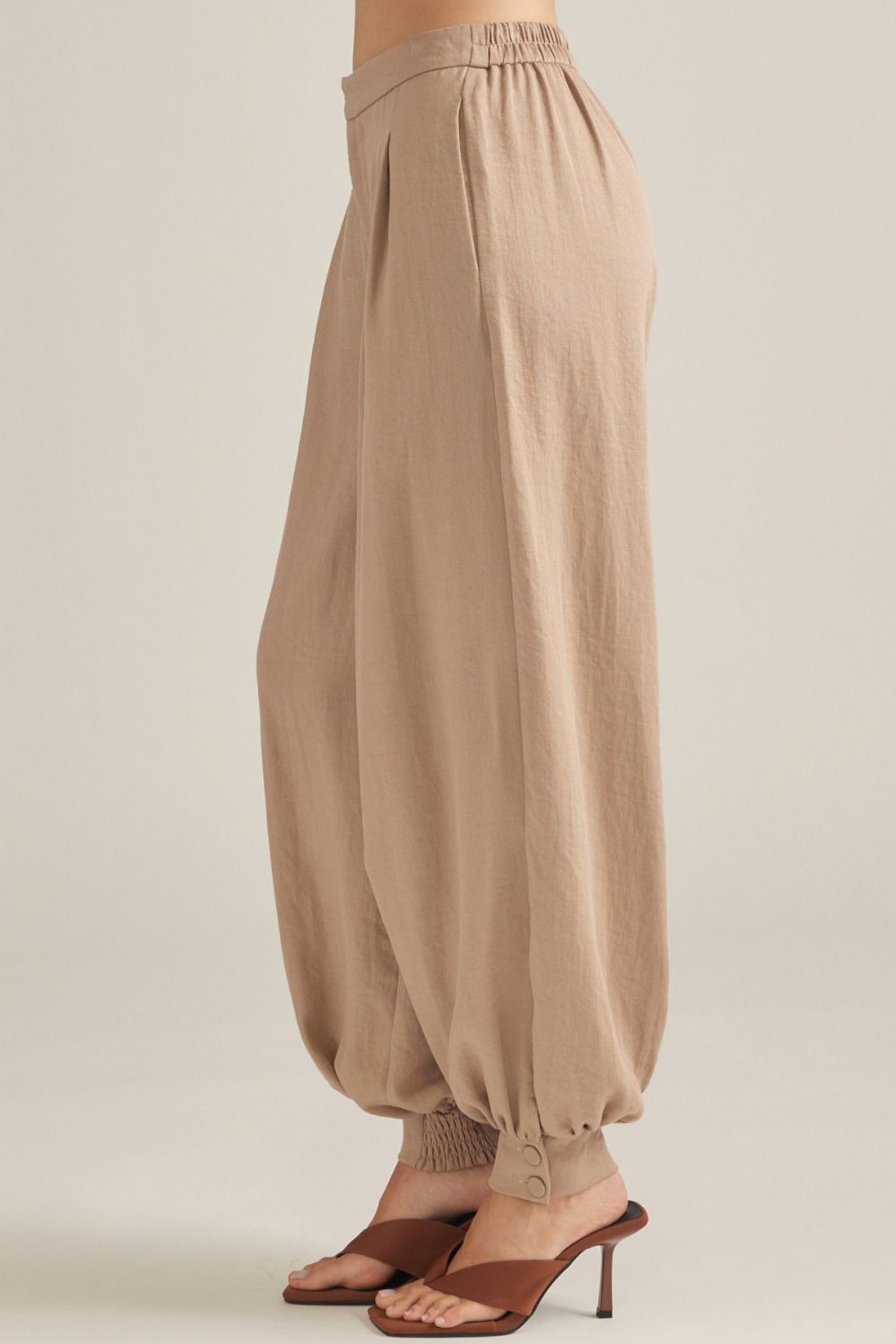 Polished woven pants featuring elegant front pleats, a comfortable elastic-back waist, and buttoned cuffs for an effortlessly tailored look.
