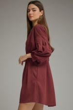 A timeless solid mini dress featuring a flattering pleated waist, classic round neckline, long sleeves, and convenient side pockets.

