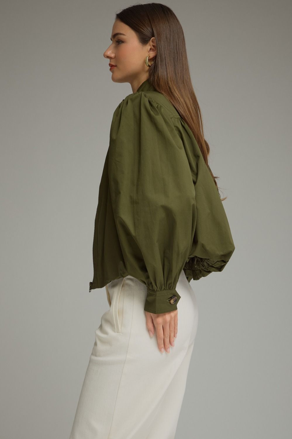 A polished everyday jacket featuring dramatic puff sleeves, a structured stand collar with a unique button closure, and a flattering elastic hem.

