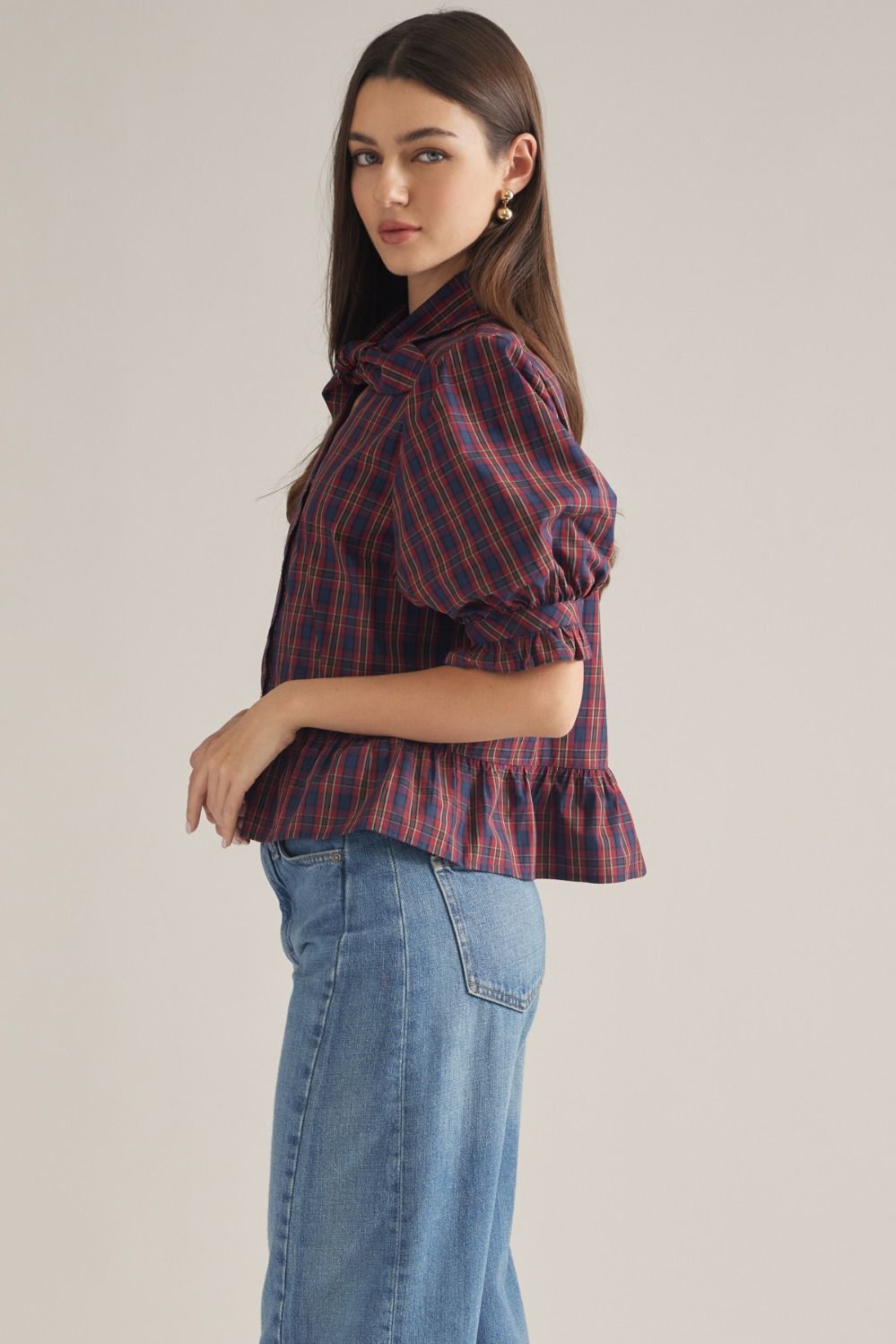 A charming plaid top featuring romantic puff sleeves, a coordinating scarf detail, ruffle hem, and classic button-front styling.