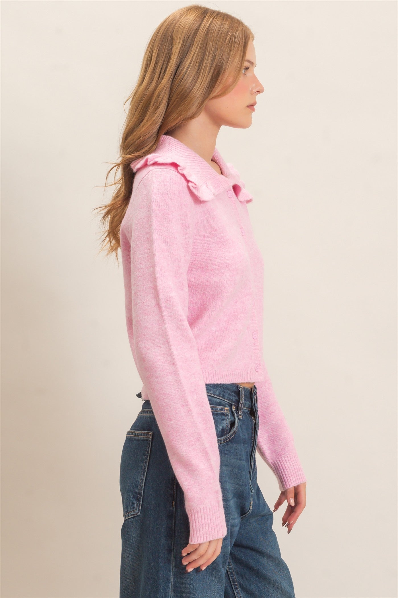 A polished knit cardigan featuring a feminine ruffled collar, classic button-front design, and ribbed cuffs for timeless everyday elegance.
