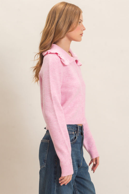 A polished knit cardigan featuring a feminine ruffled collar, classic button-front design, and ribbed cuffs for timeless everyday elegance.
