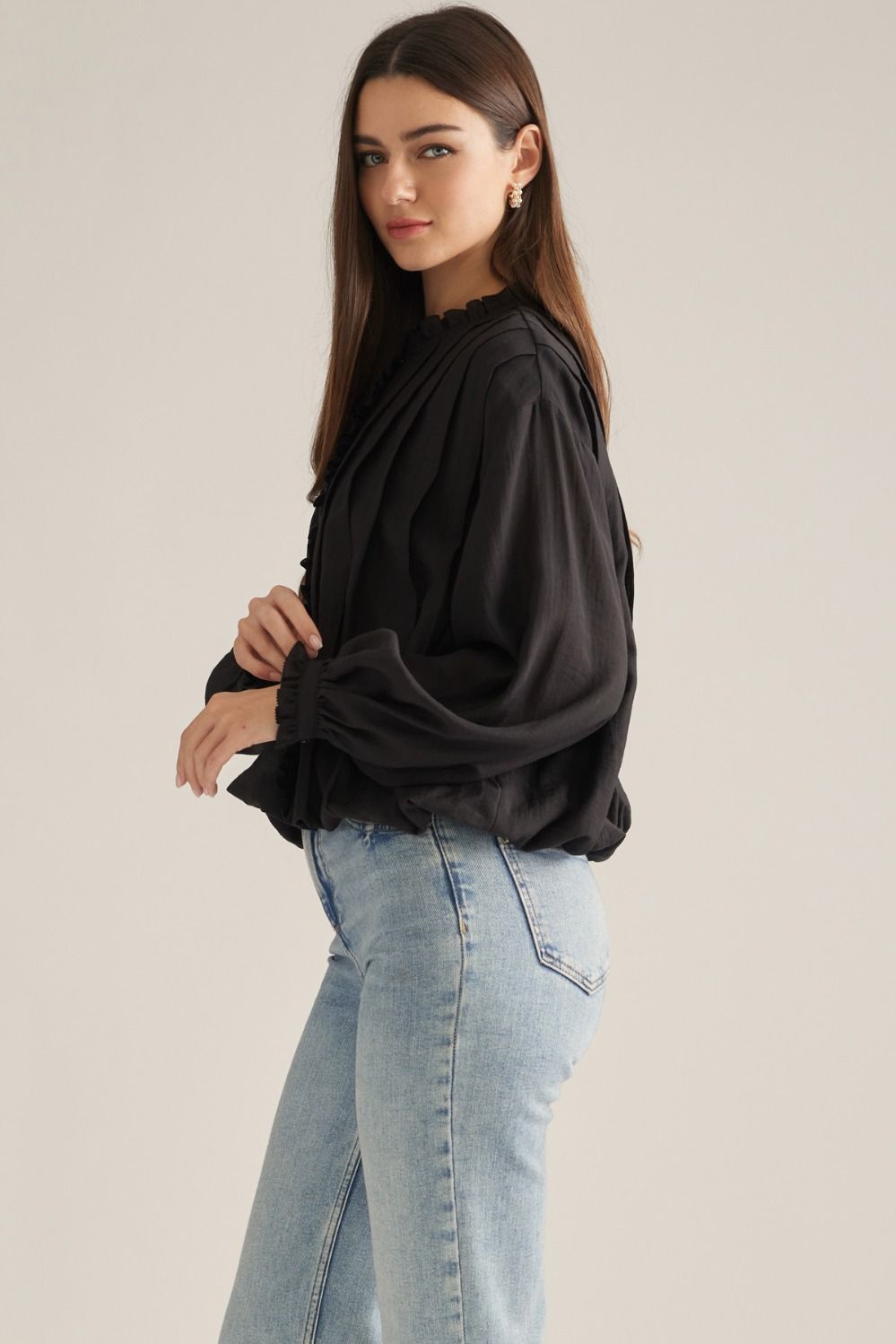 A romantic long-sleeve blouse featuring a ruffled high neckline, delicate front ruffle trim, and elegant button details for a timeless feminine look.

