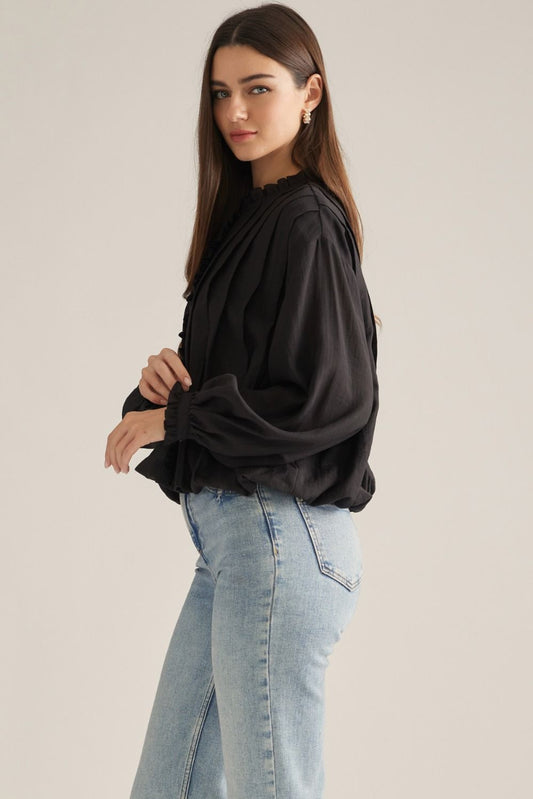 A romantic long-sleeve blouse featuring a ruffled high neckline, delicate front ruffle trim, and elegant button details for a timeless feminine look.

