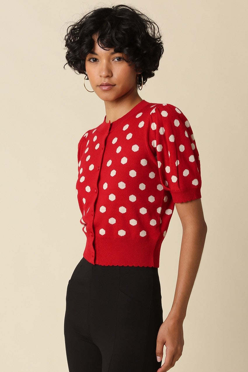 A feminine cropped polka dot cardigan featuring short puff sleeves, a scalloped hem, and a flattering fitted silhouette in a soft stretch wool blend.