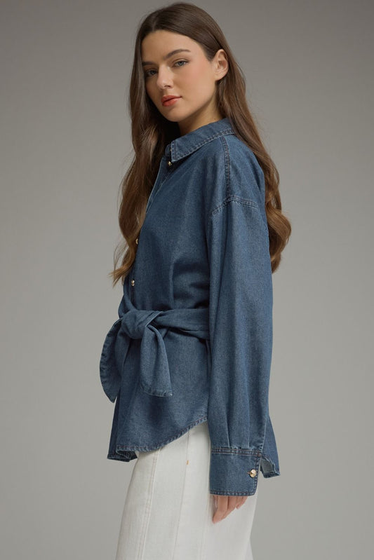 A chic lightweight denim top featuring a classic button front, flattering wraparound self-tie waist, and polished button cuffs.

