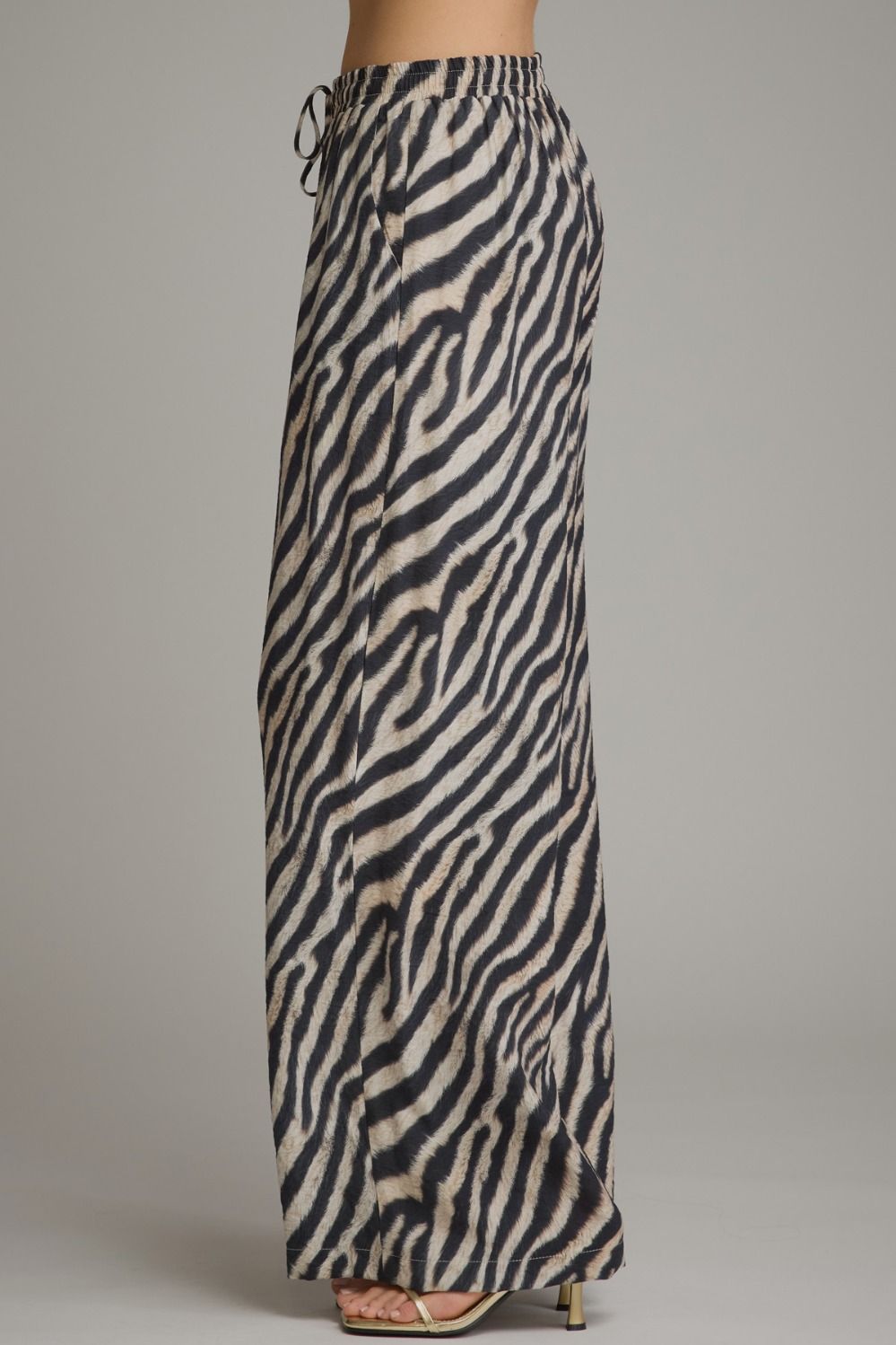 Make a bold statement in these lightweight zebra print wide leg pants featuring a comfortable elastic waistband and adjustable drawstring detail.