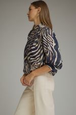 A statement-making zebra print top featuring elegant ¾ balloon sleeves, a stand collar, gathered details, and a polished banded hem.

