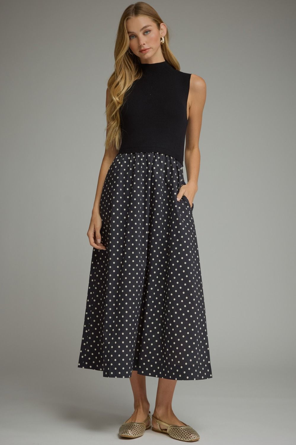 A sophisticated polka dot midi dress featuring a sleek solid knit bodice, mock neckline, and feminine flowing silhouette.


