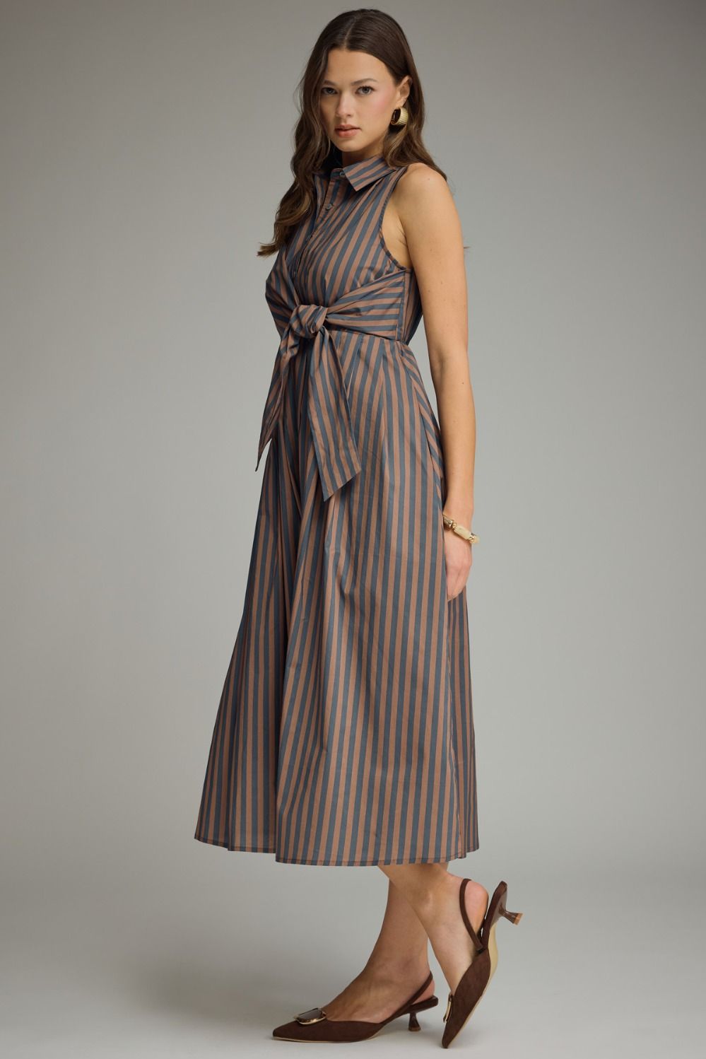 A timeless striped midi dress featuring a collared neckline, self-tie front, and sleeveless silhouette for effortless warm-weather style.
