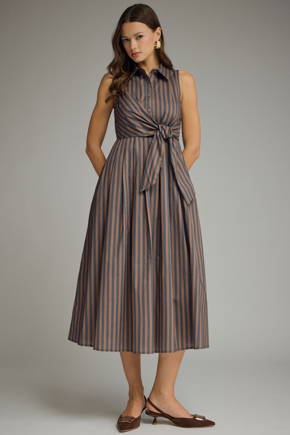 A timeless striped midi dress featuring a collared neckline, self-tie front, and sleeveless silhouette for effortless warm-weather style.
