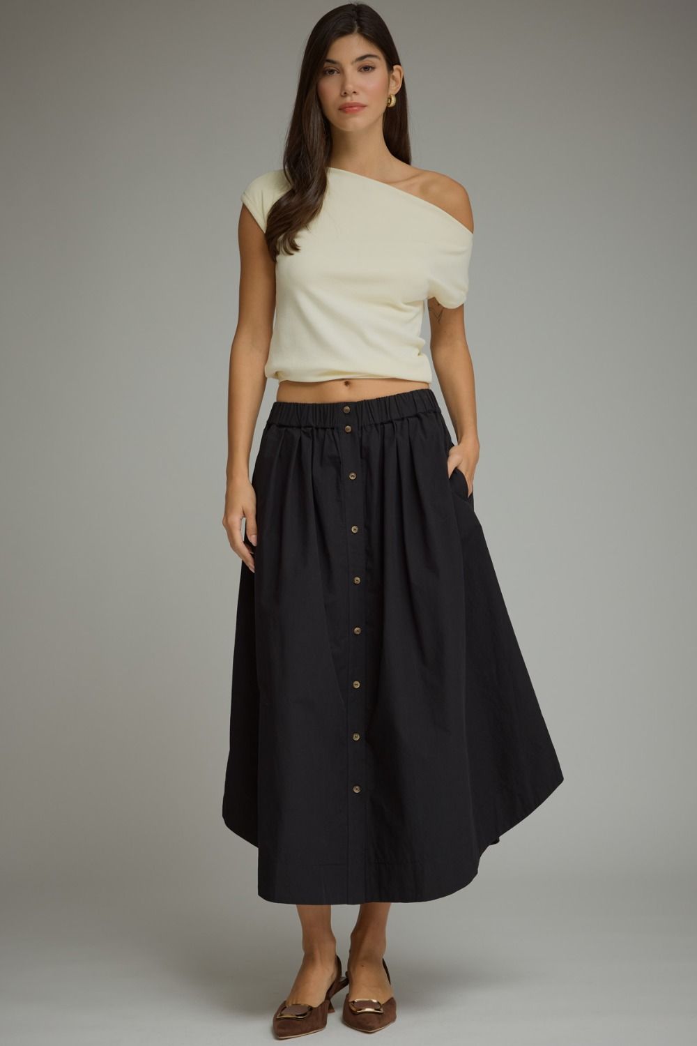 A timeless midi skirt featuring a button-front design, comfortable elastic waistband, and functional side pockets for effortless everyday elegance.

