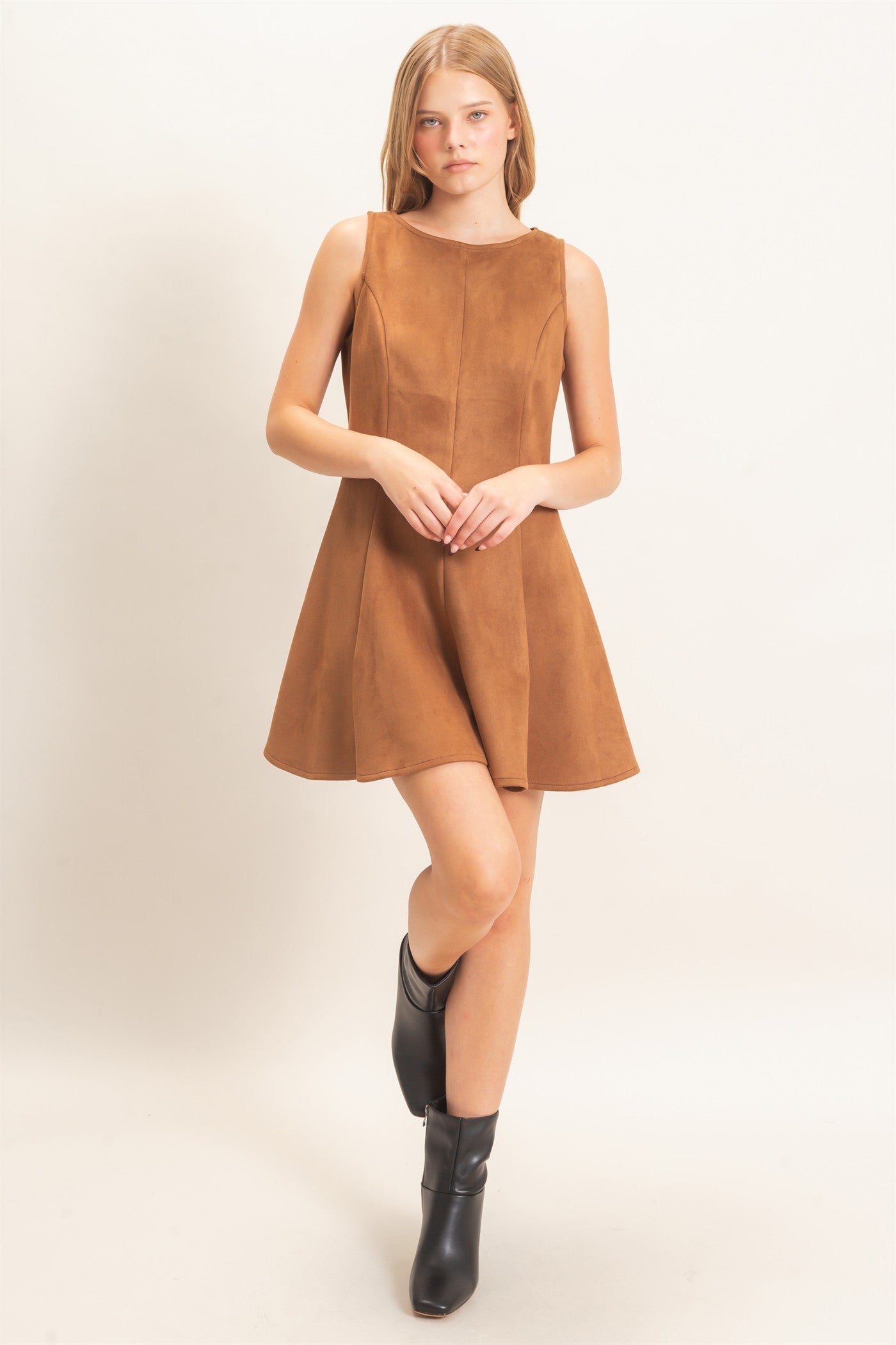 A sophisticated sleeveless suede mini dress with a classic round neckline and flattering flared silhouette that effortlessly transitions from day to night.
