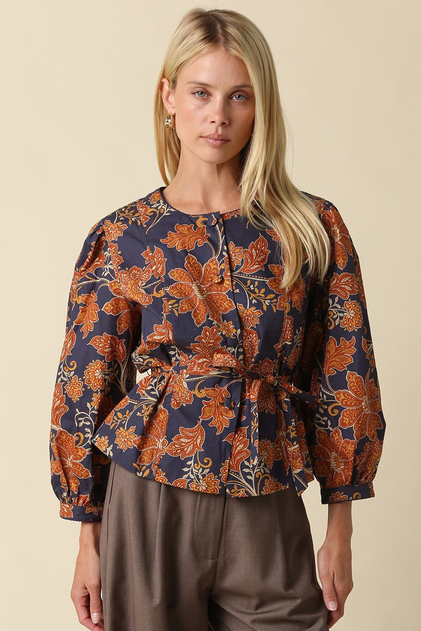 A feminine floral blouse featuring puff sleeves, a flattering peplum silhouette, and a front tie waist for an effortlessly polished look.

