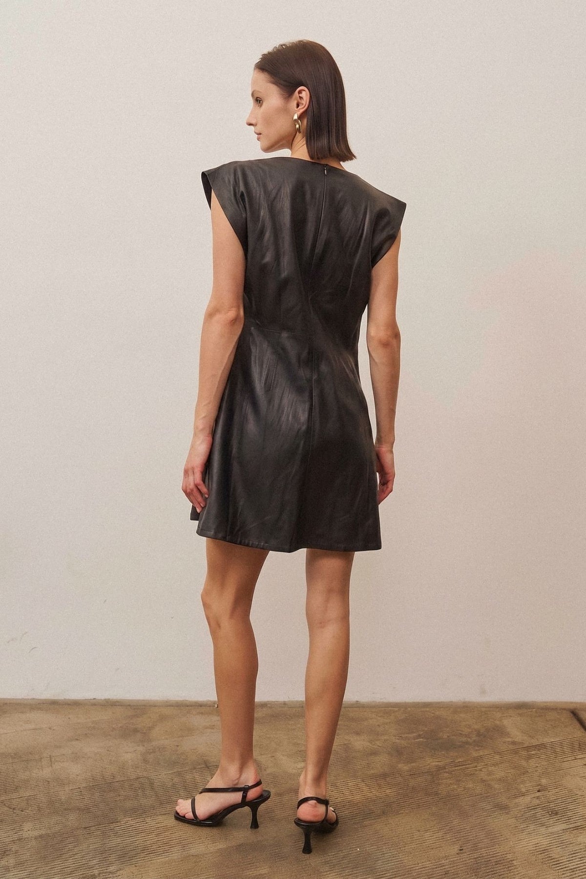 A sleek vegan leather mini dress featuring a subtle shimmering finish for a chic, statement-making look.