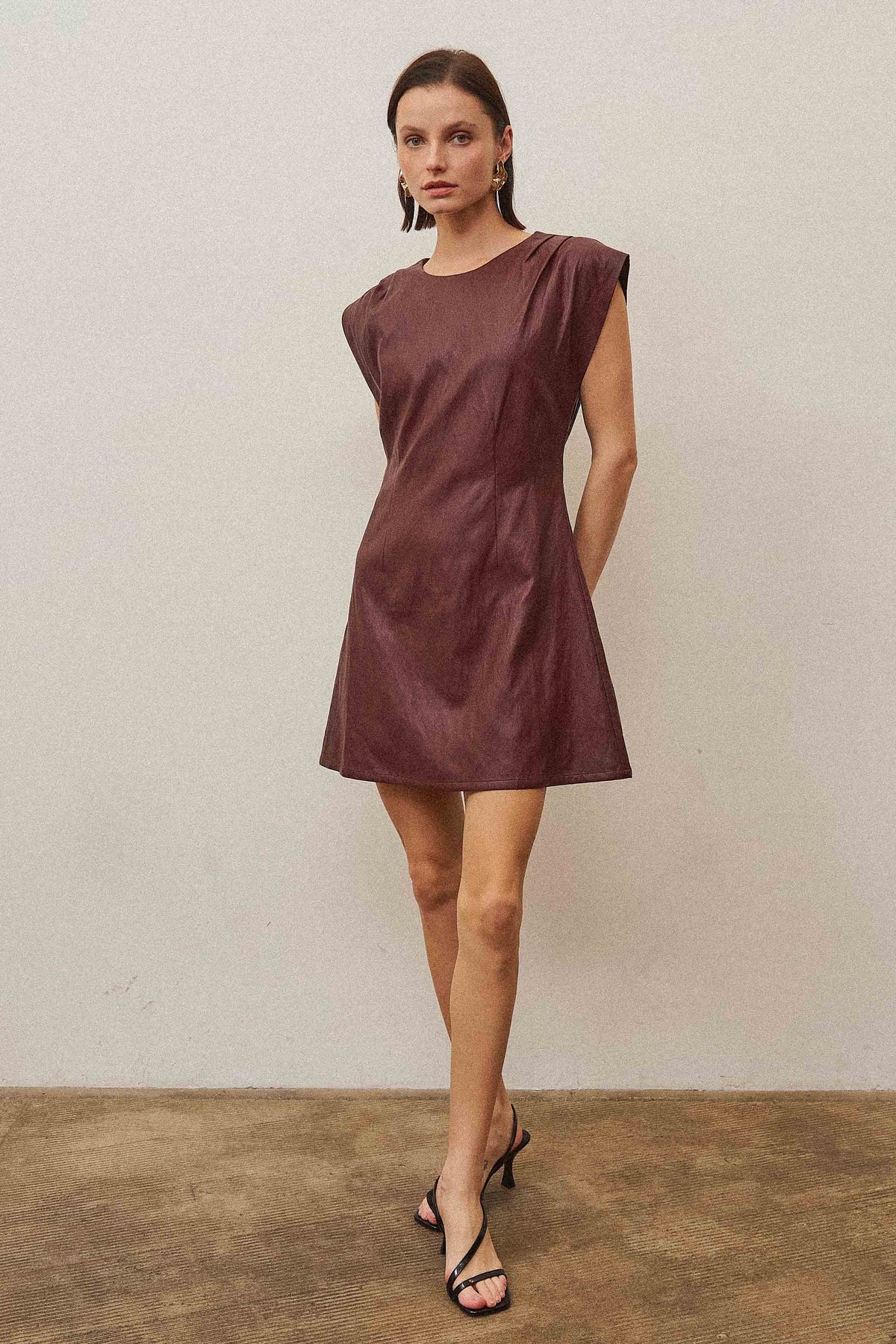 A sleek vegan leather mini dress featuring a subtle shimmering finish for a chic, statement-making look.