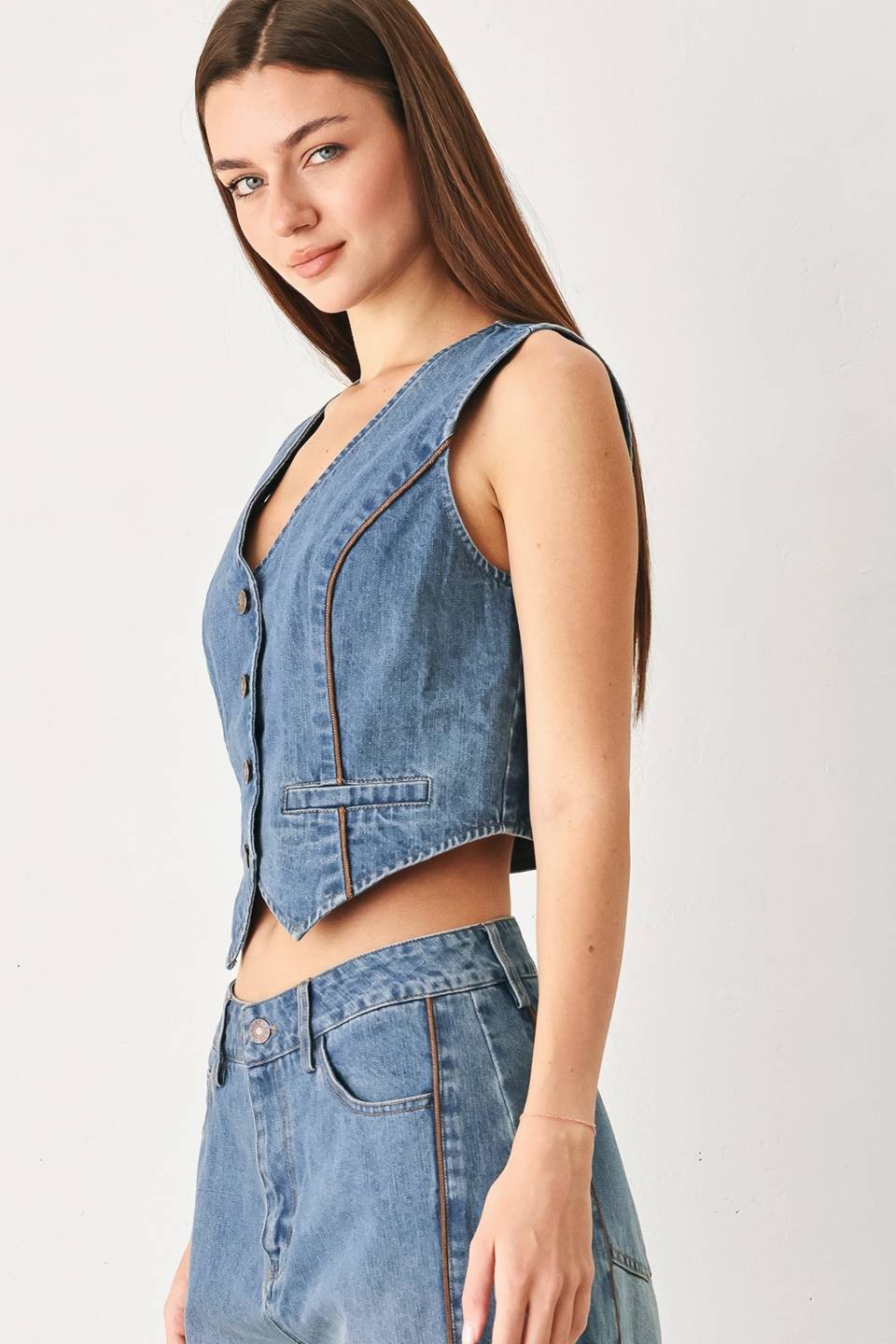 Model wearing the Winslet Washed Denim Vest featuring a washed cotton-blend denim finish, front button closure, tailored fit, and piping detail from Pieces & Peaches boutique.