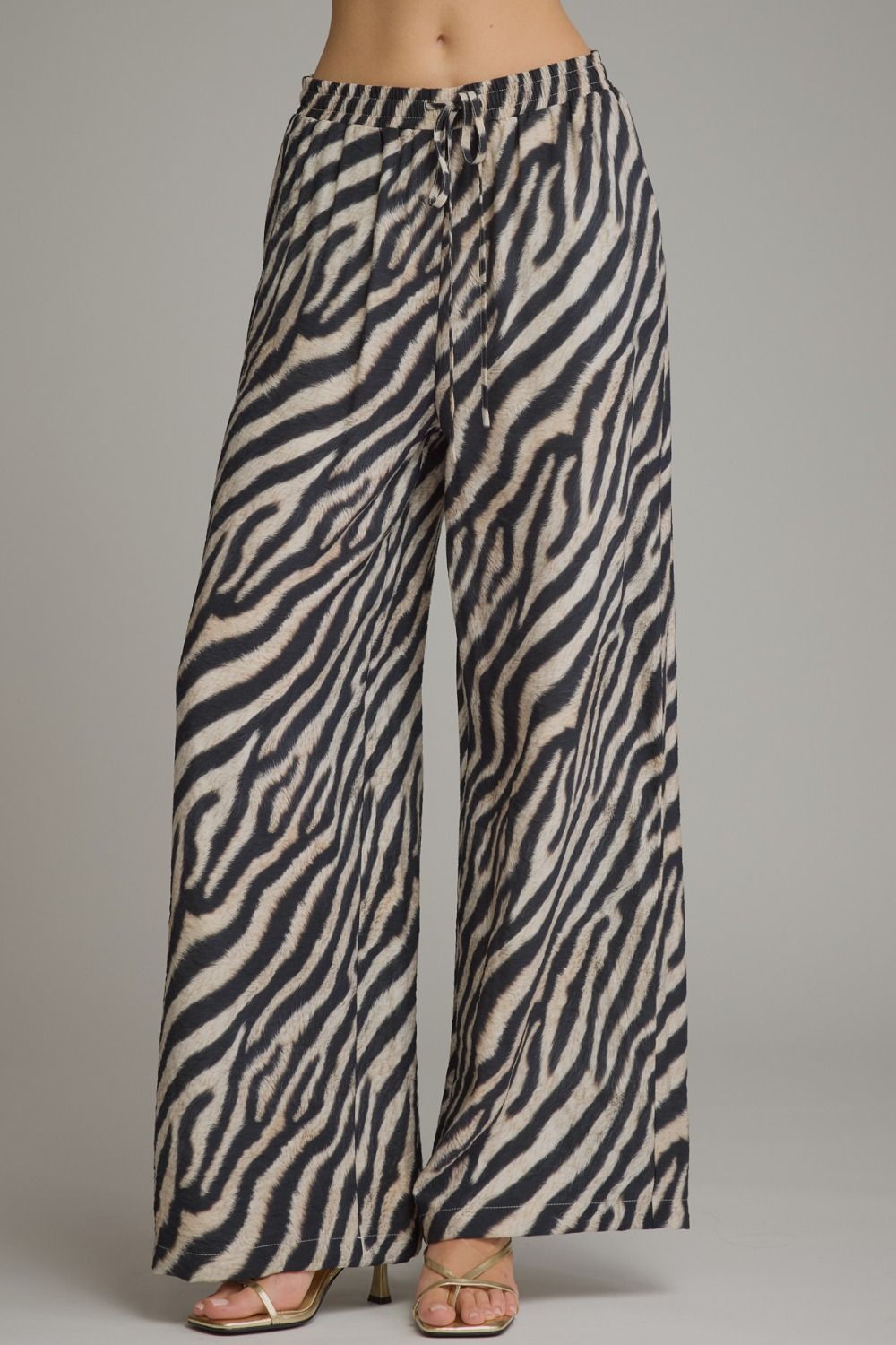 Make a bold statement in these lightweight zebra print wide leg pants featuring a comfortable elastic waistband and adjustable drawstring detail.